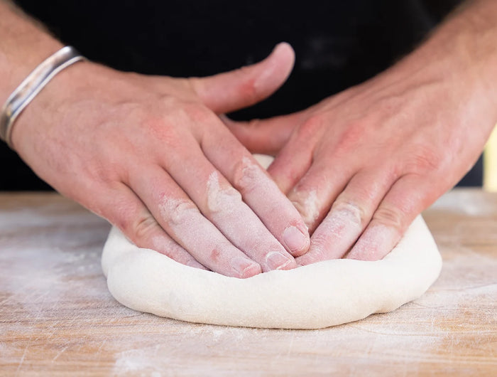 A person kneading a pizza dough.